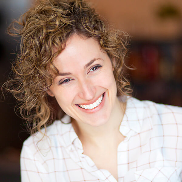 A woman smiling with curly hair.