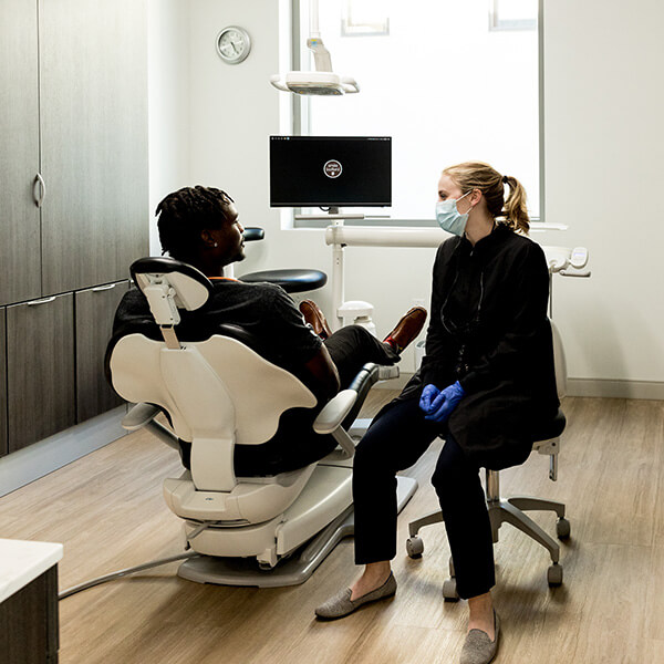Dr. Merritt is talking to a patient sitting in the dentist's chair.